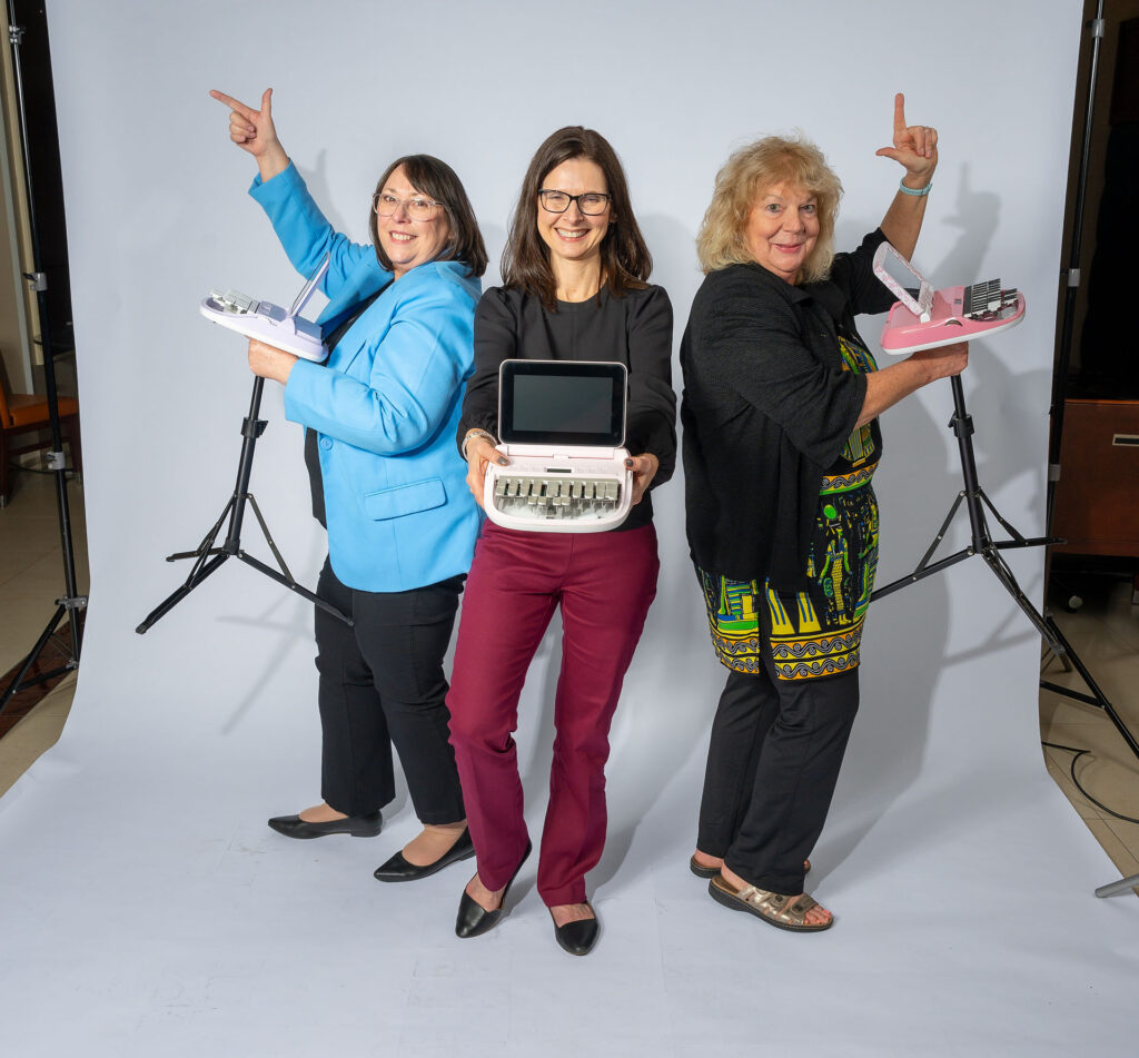 Three reporters posing like Charlie's Angels with their steno machines