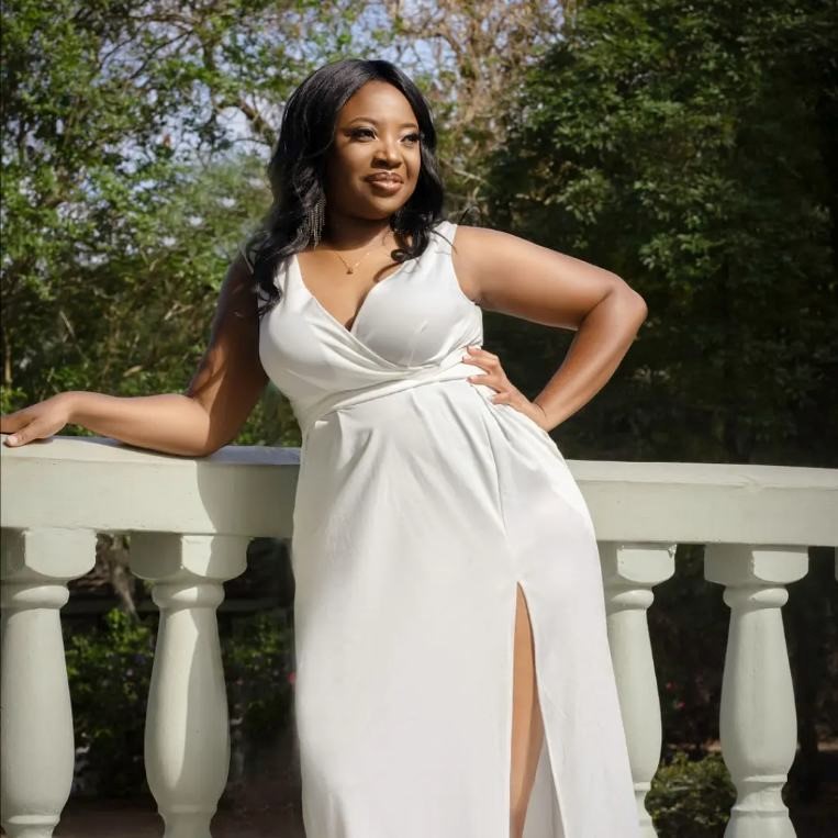 Vanese Killingbeck posing in a white dress on a balcony