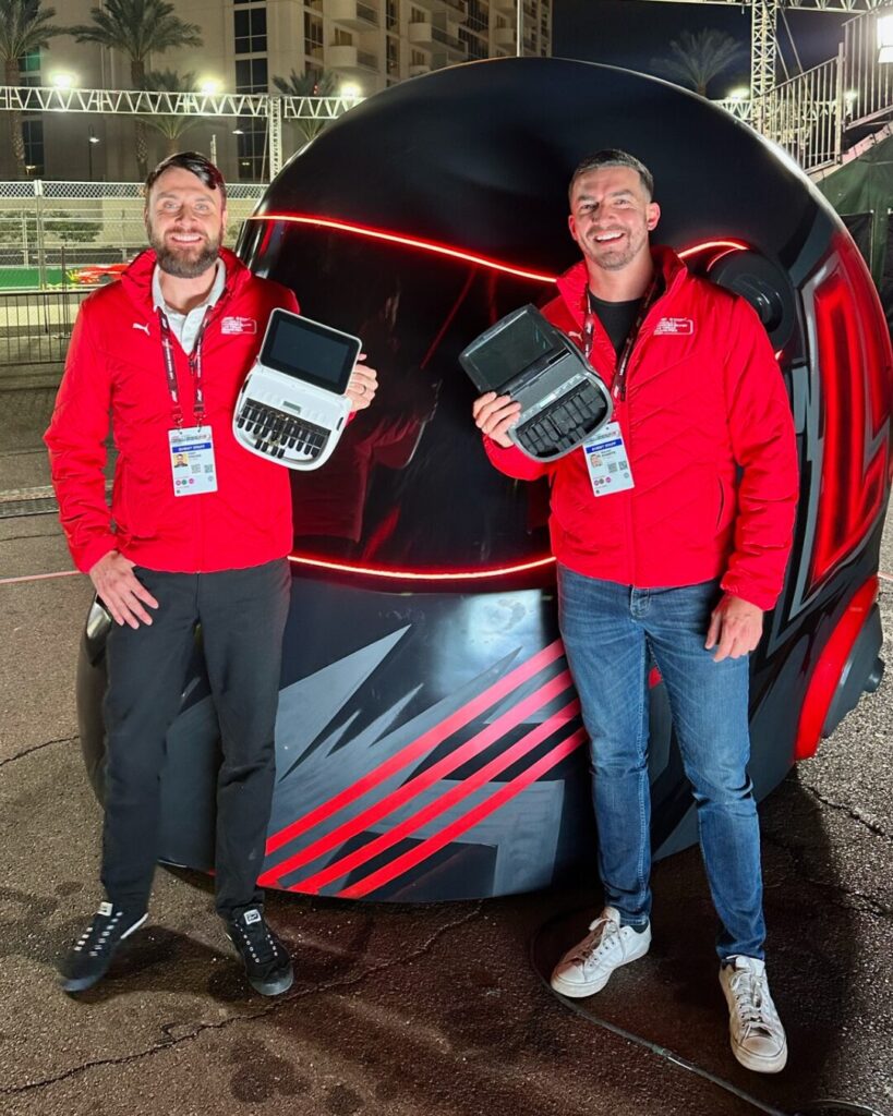 Cody Knacke (left) and Isaiah Roberts (right) posing in front of oversized car racing helmet